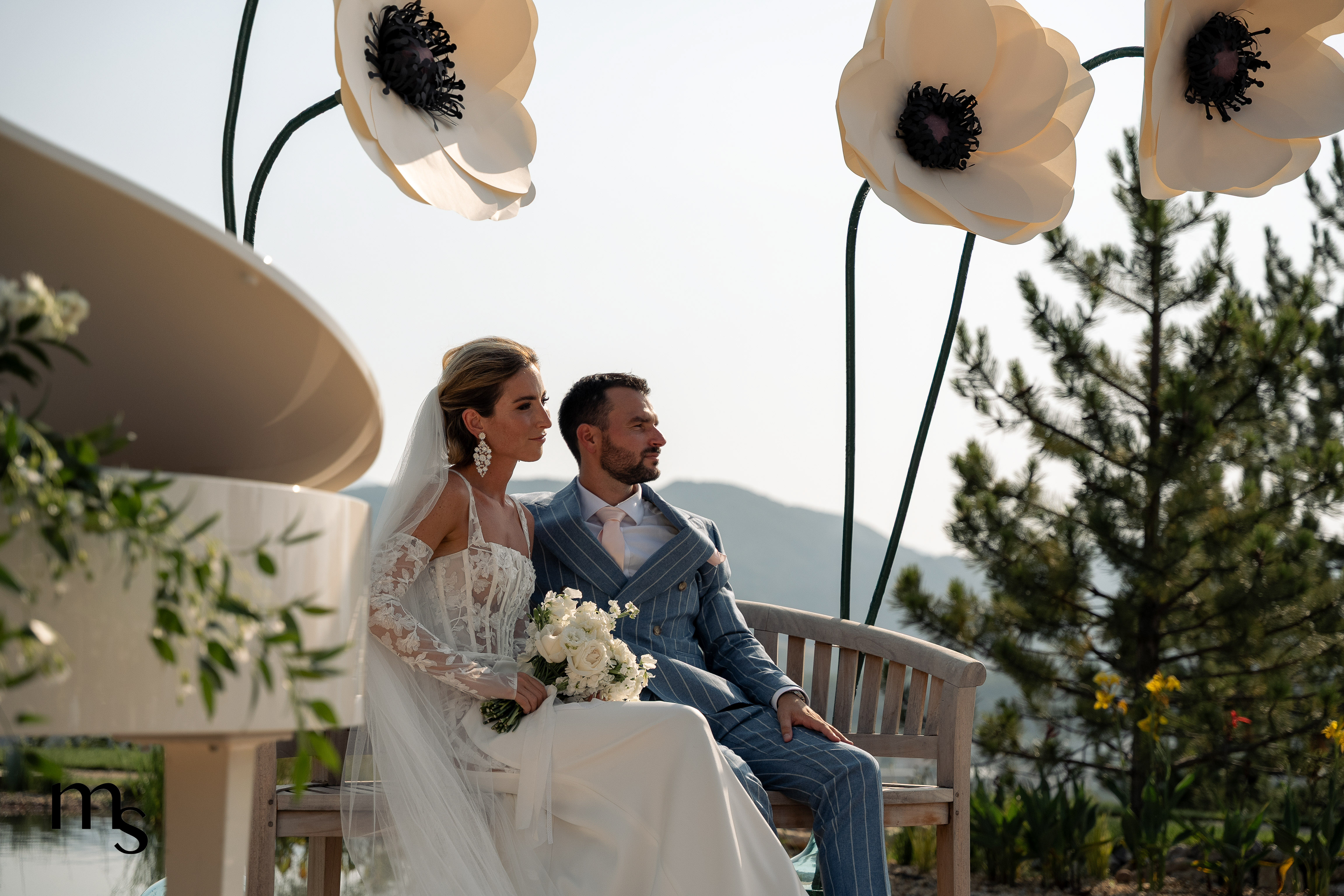 mariés entourés d'immenses fleurs en papier, au bord du lac, pendant leur cérémonie laïque au Mas des Cinq Fontaines, à Sisteron