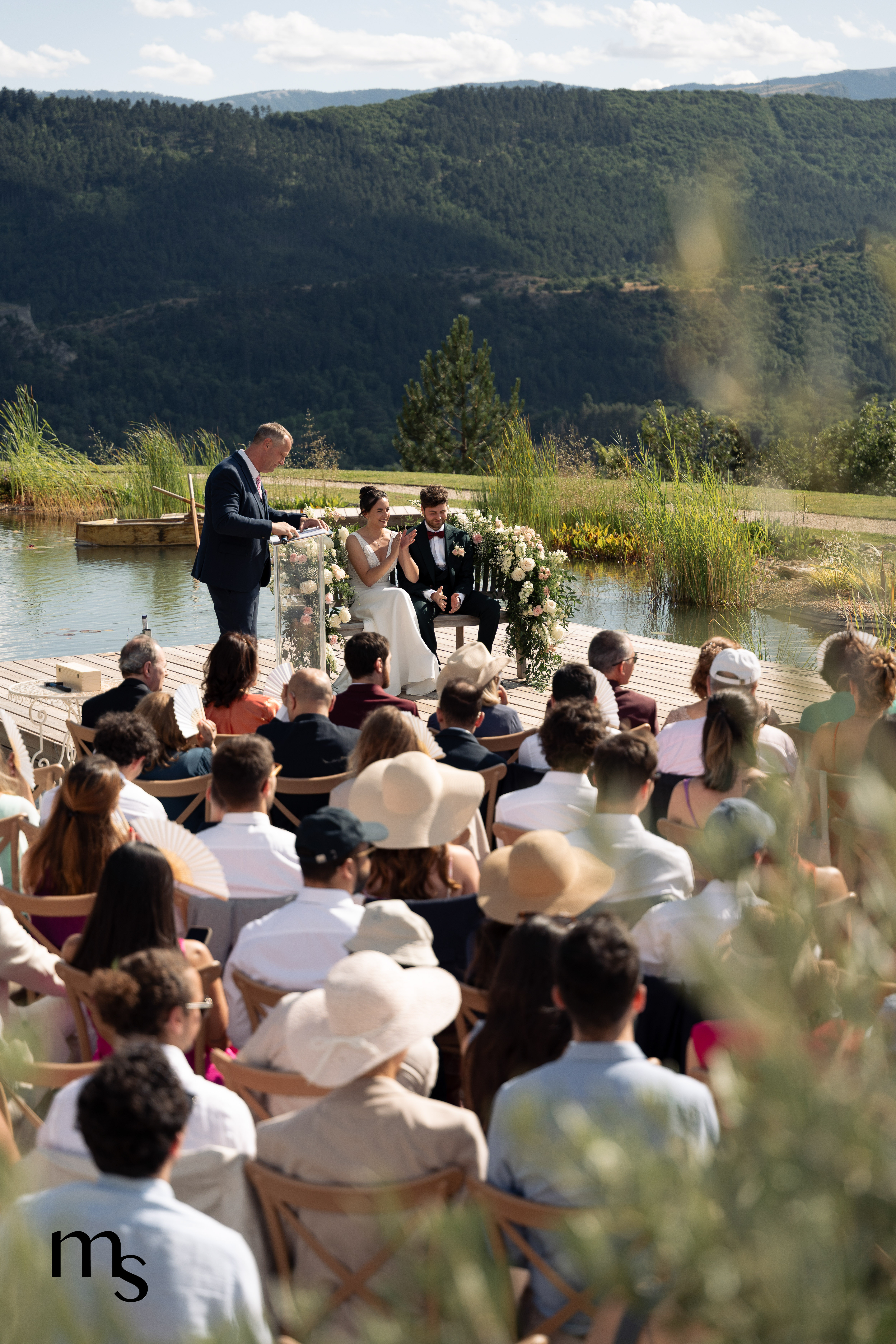 mariés et officiant se tenant près du lac lors de la cérémonie laïque au Mas des Cinq Fontaines à Sisteron