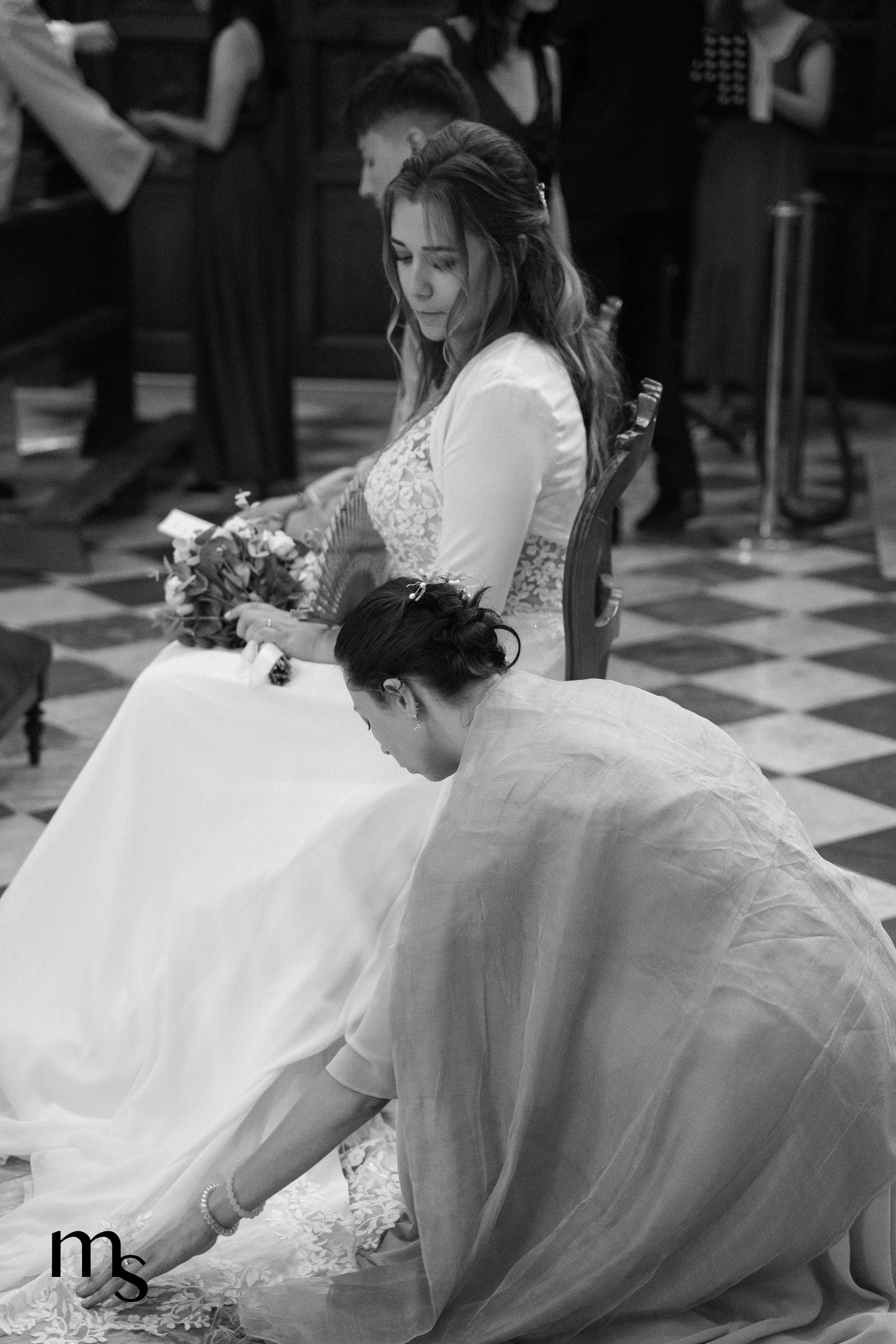 témoin replaçant la robe de la mariée pendant la cérémonie dans une église du Var