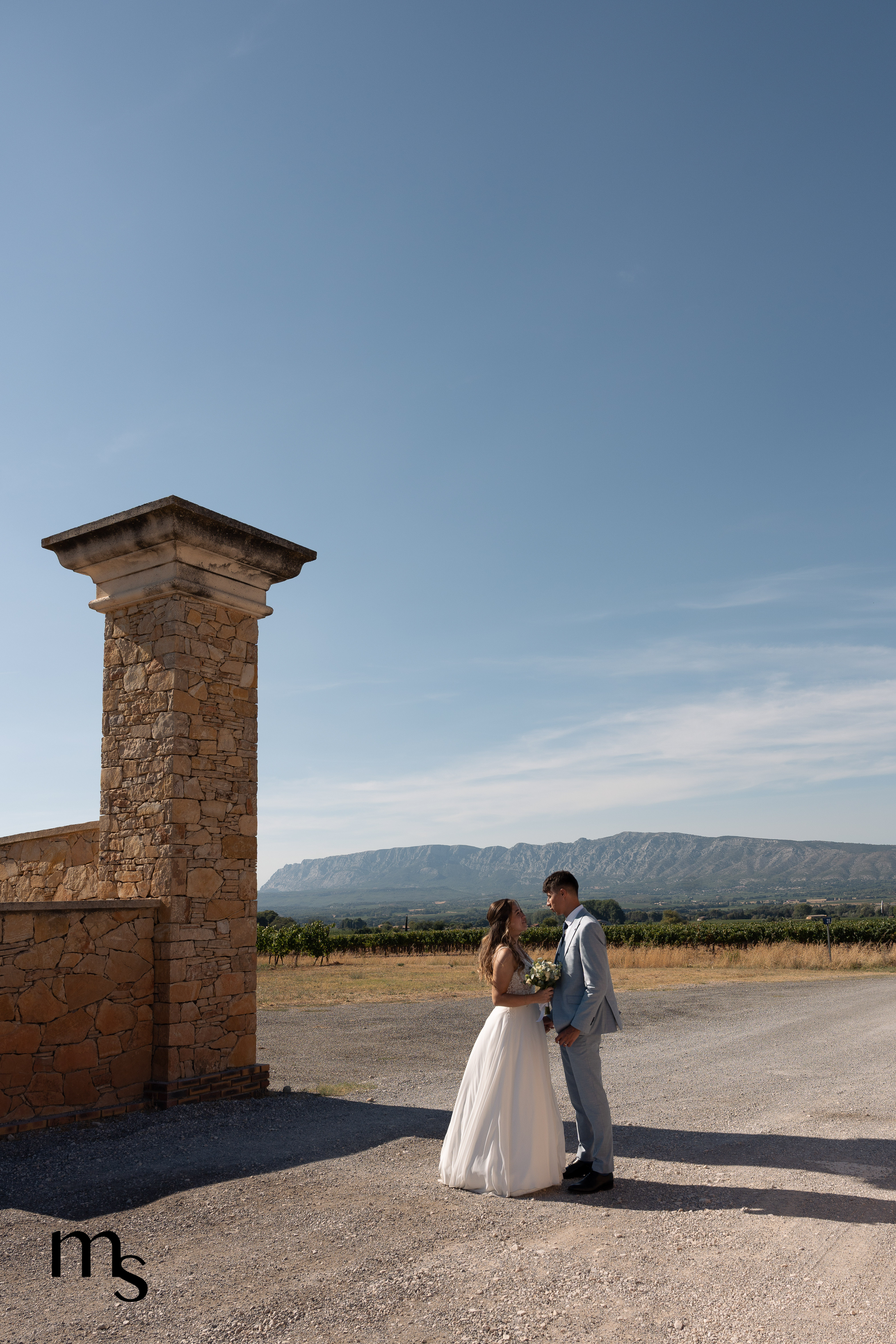mariés se regardant et s'enlaçant devant l'entrée d'un château en Provence