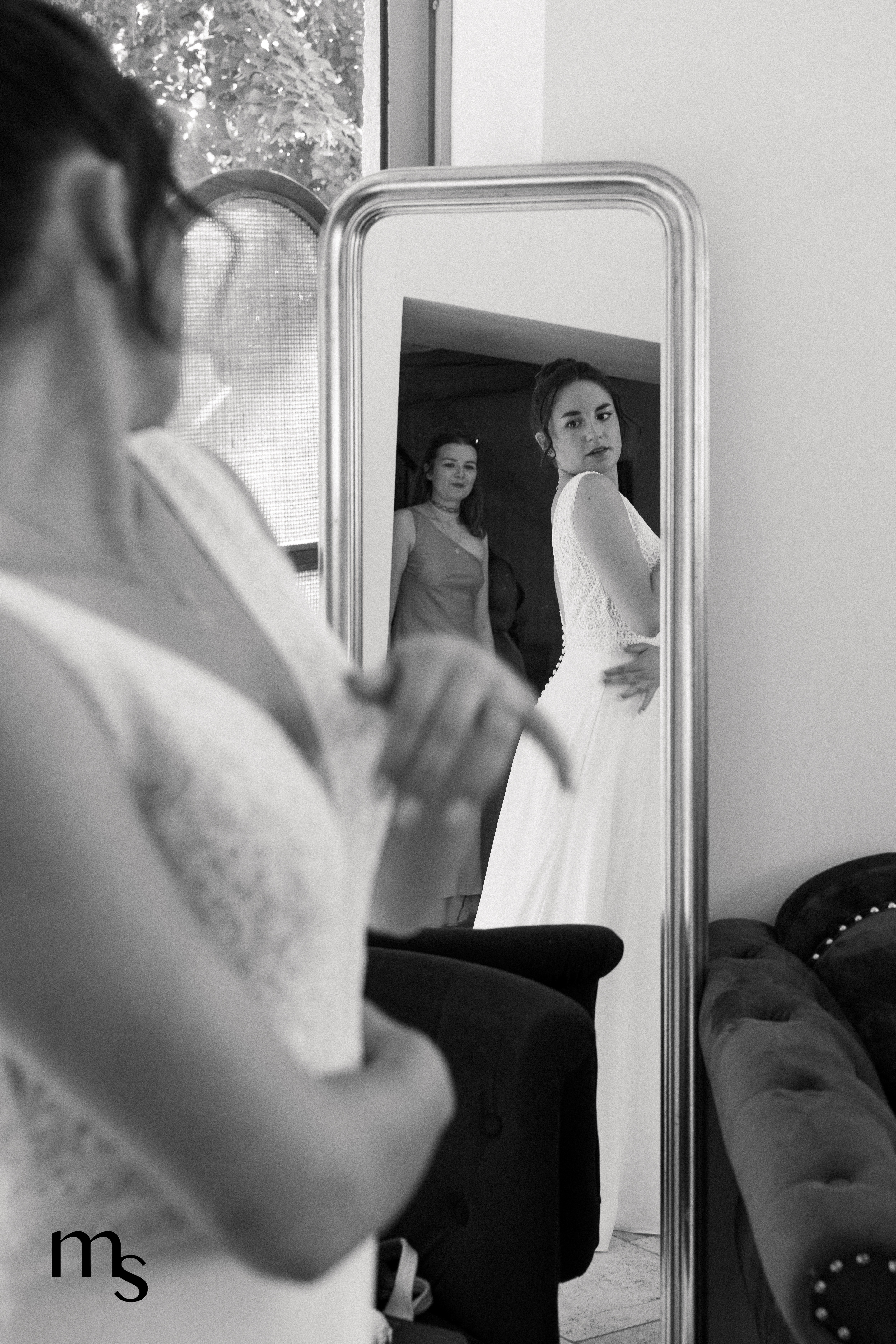 mariée se regardant dans le miroir après avoir enfilé sa robe