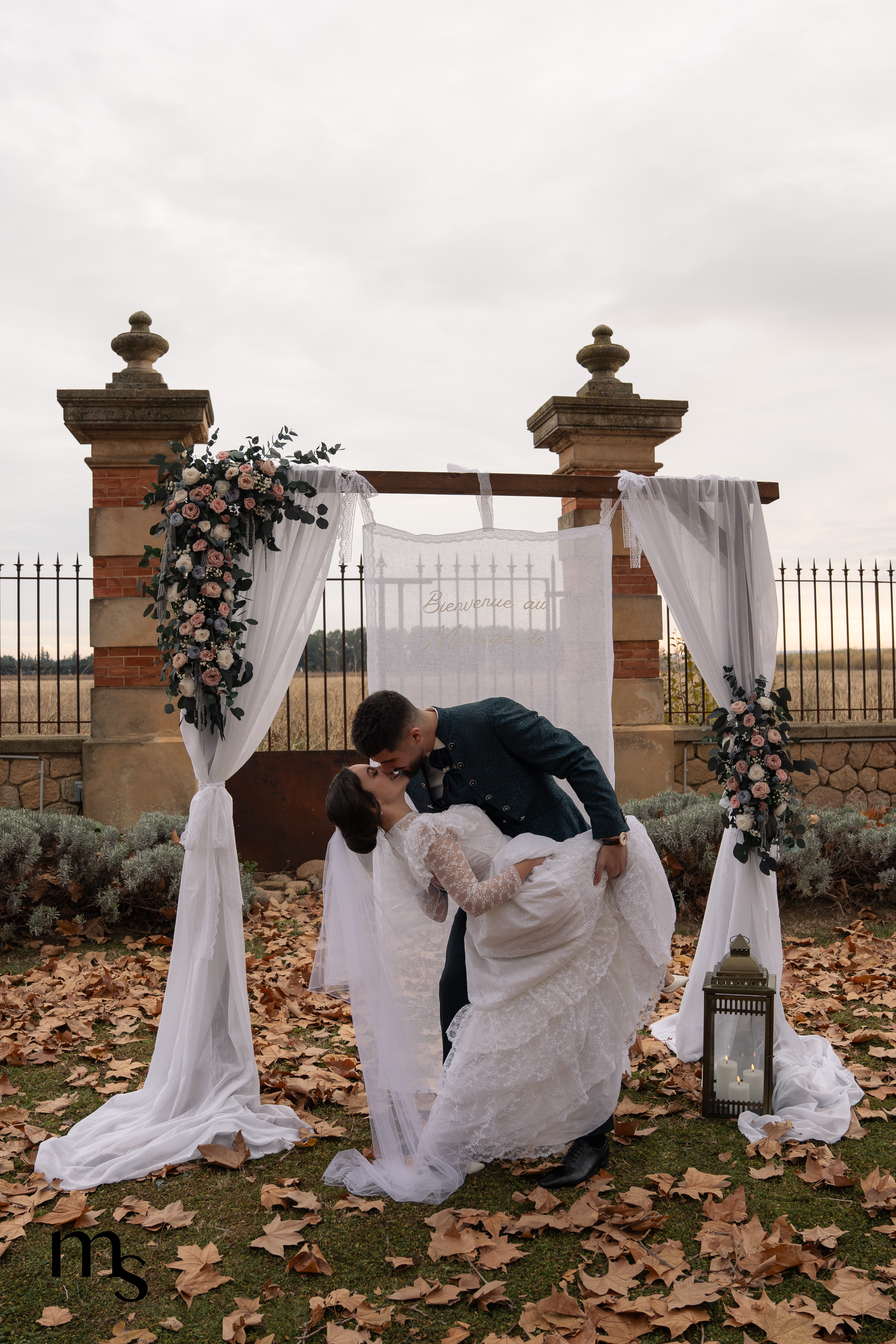 mariés s'embrassant sous l'arche à la fin de la cérémonie laïque au chateau de la Beaumetane